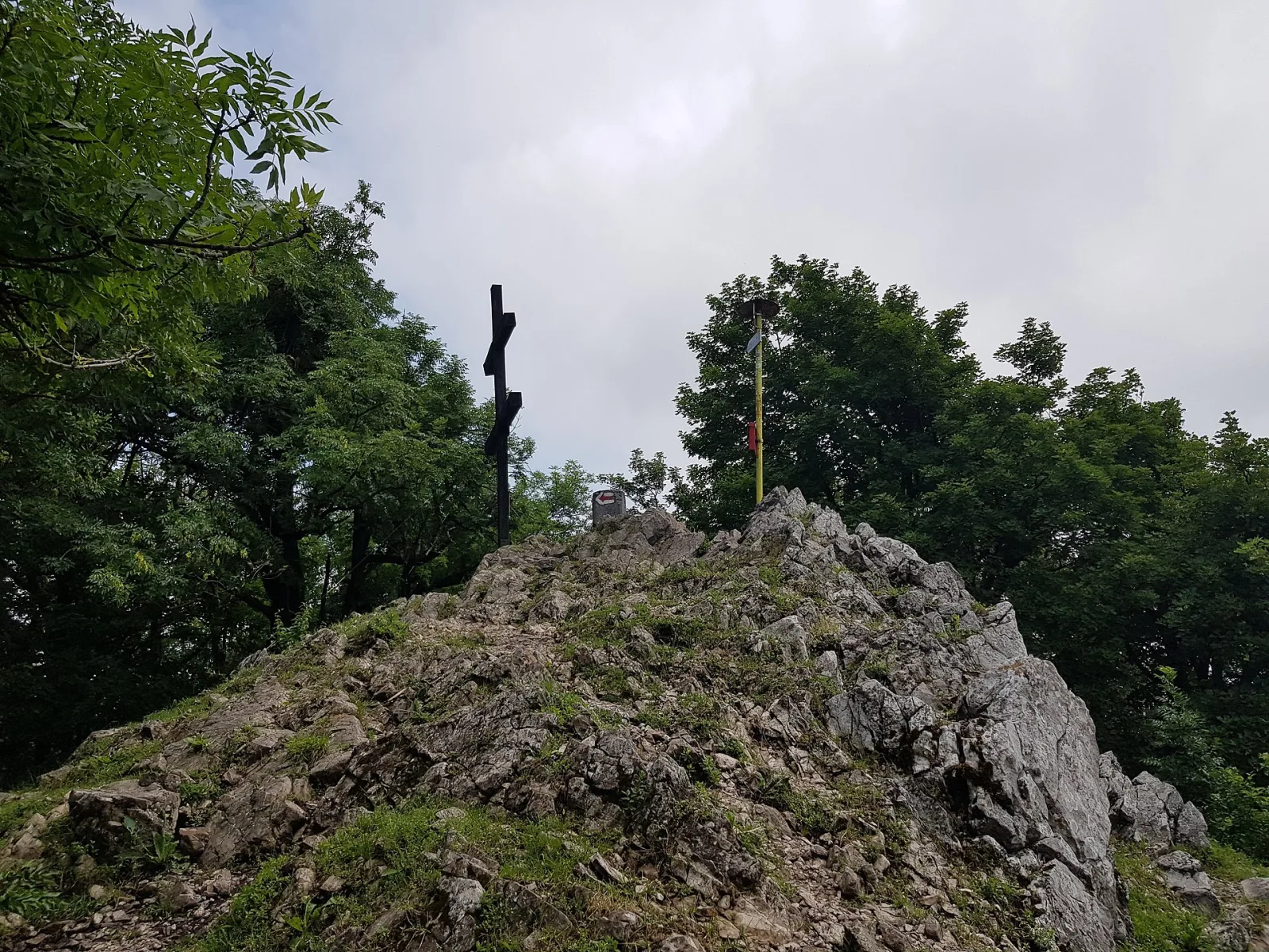 Skalnatý vrchol Zárub s krížom medzi stromami, najvyšší bod Malých Karpát